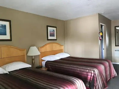 a hotel room with two beds and a lamp at Bulkley Valley Motel in New Hazelton