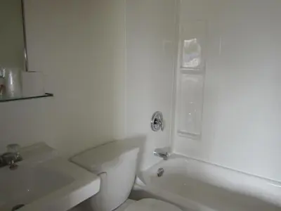 a white bathroom with a toilet and a sink at Bulkley Valley Motel in New Hazelton