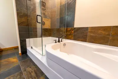 a white bath tub in a bathroom with a shower at Creekside 2-Bedroom Condo in Canmore