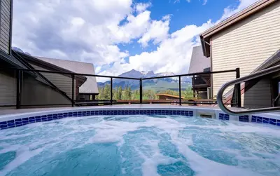 a hot tub on the patio of a house at Creekside 2-Bedroom Condo in Canmore