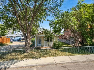a house with a fence in front of a yard at The Canary 2BR Gem in Downtown Drumheller in Drumheller