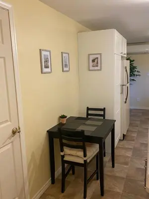 a dining room table with two chairs and a refrigerator at Ravens Nest Cozy Lower One Bedroom Suite in Victoria