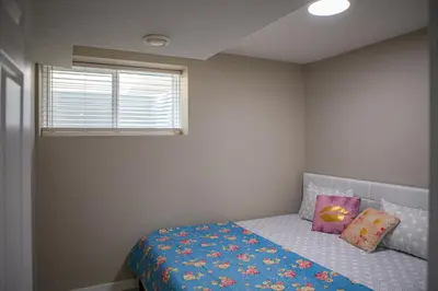 a bedroom with a bed with a blue blanket and a window at Modern 2-Bedroom Suite with Private Access - 10 minutes from Calgary Airport in Calgary
