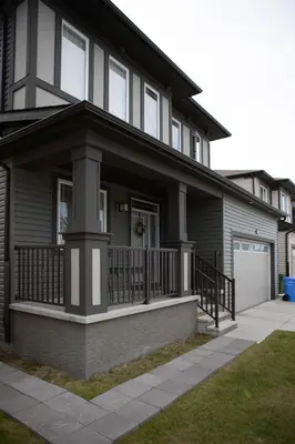 a black house with a porch and a garage at Modern 2-Bedroom Suite with Private Access - 10 minutes from Calgary Airport in Calgary