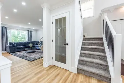 a staircase in a living room with a blue couch at Valley Villa Spacious 5BD Getaway! Sleep 12, 1hr to Banff, 40 Mins Canmore, 5 mins to WinSport & Olympic park in Calgary