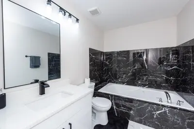 a white bathroom with a tub and a toilet and a sink at Valley Villa Spacious 5BD Getaway! Sleep 12, 1hr to Banff, 40 Mins Canmore, 5 mins to WinSport & Olympic park in Calgary