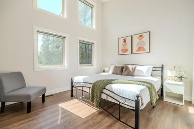 a bedroom with a bed and a chair and windows at Mountain View Hideaway - BBQ, Beach Access in Invermere