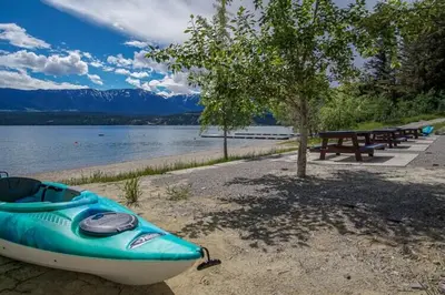 a blue kayak sitting on the shore of a lake at Mountain View Hideaway - BBQ, Beach Access in Invermere