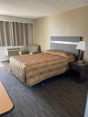 a hotel room with a bed and a chair at Hilltop Motor Inn in Elk Point