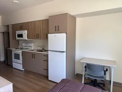 a kitchen with a white refrigerator and a table at Residence & Conference Centre - Kelowna in Kelowna