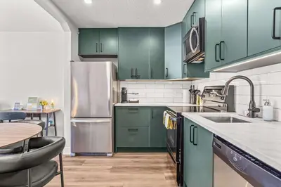 a kitchen with green cabinets and a stainless steel refrigerator at Mountain Views Balcony and Free Parking in Canmore