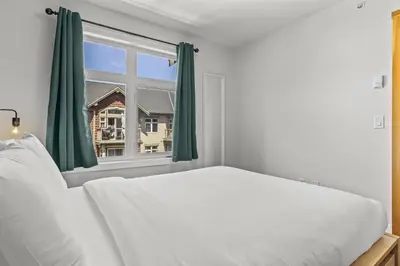 a bedroom with a white bed and a window at Mountain Views Balcony and Free Parking in Canmore