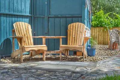 two wooden chairs and a table in front of a building at Sunny Shuswap B&B in Chase