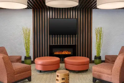 a lobby with a fireplace and two chairs and a tv at Holiday Inn Express & Suites Cold Lake by IHG in Cold Lake