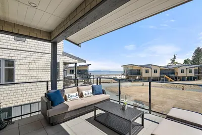 a patio with a couch and a table on a balcony at I Beach You To It in Oyster Bay