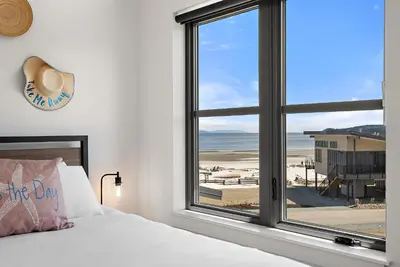 a bedroom with a bed and a window with a view of the beach at I Beach You To It in Oyster Bay