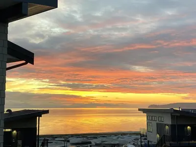 a sunset over the water with buildings and the ocean at I Beach You To It in Oyster Bay