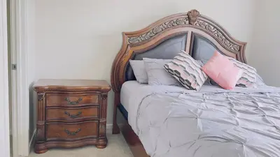 a bed with a wooden headboard next to a night stand at Calgary Airport Getaway Spacious 3BR Full Home in Calgary