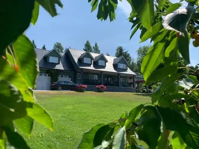a house with a green yard with a car in front at Remo Ridge Bed N Breakfast in Terrace