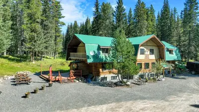 a log cabin with a green roof and a parking lot at HI Nordegg - Hostel in Nordegg