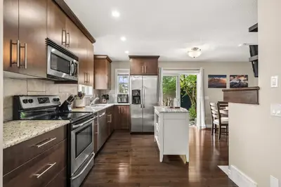 a kitchen with stainless steel appliances and wooden cabinets at Social Haus Trendy 3BR Townhome in Bridgeland YYC in Calgary