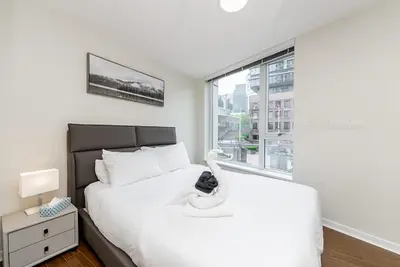 a bedroom with a large white bed with a window at Spacious Downtown Condo with Pool Gym & Parking in Vancouver