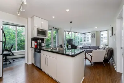 a kitchen with a counter top and a living room at Spacious Downtown Condo with Pool Gym & Parking in Vancouver