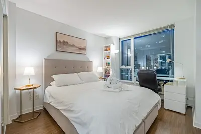 a bedroom with a bed and a chair and a window at Downtown Condo with Great City Views in Vancouver