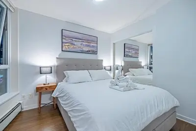 a white bedroom with a large bed and a window at Downtown Condo with Great City Views in Vancouver