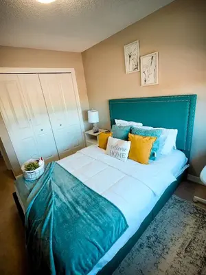 a bedroom with a large bed with blue sheets and yellow pillows at Stonecroft House in Calgary