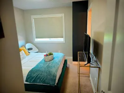 a bedroom with a bed with a television and a table at Stonecroft House in Calgary