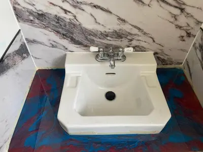 a white sink in a bathroom with a marble wall at Cabernet Sauvignon Escape in Calgary