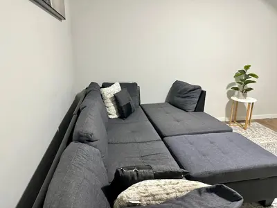 a grey couch with pillows in a living room at The Seton Nook - 1BR Suite Near Seton Health Campus, Cineplex and YMCA in Calgary