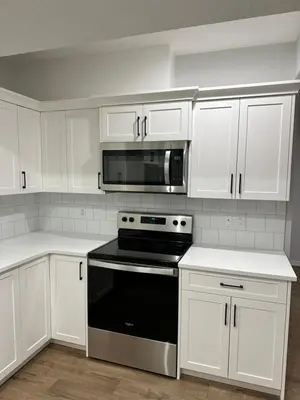 a white kitchen with a stove and a microwave at The Seton Nook - 1BR Suite Near Seton Health Campus, Cineplex and YMCA in Calgary
