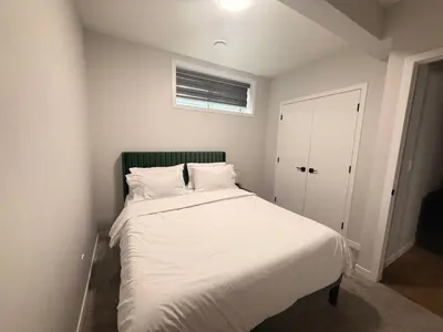 a bedroom with a bed with white sheets and a window at The Seton Nook - 1BR Suite Near Seton Health Campus, Cineplex and YMCA in Calgary