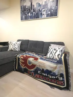 a couch with a football blanket on top of it at Haven YYC Guest Suite in Northwest Calgary in Calgary