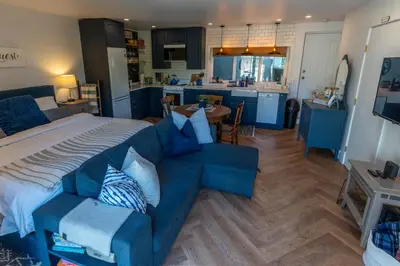a bedroom with a bed and a couch and a kitchen at Garden Cottage and Bunkie at Horner Park in Victoria
