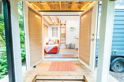 a tiny house with a hallway leading to a bedroom at Riverwood Retreat-hot tub and cedar sauna on the river in Squamish