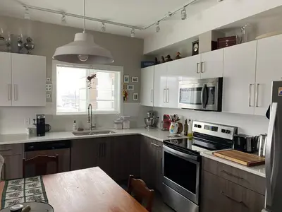 a kitchen with white cabinets and a wooden table at Heart of Vernon in Vernon