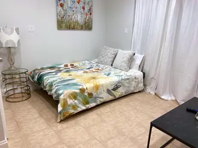 a bedroom with a bed with a floral comforter at Bright 1-Bedroom Garden Suite, Sleeps 4, Near Downtown & YVR in Vancouver