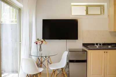 a kitchen with a table and a tv on the wall at Bright 1-Bedroom Garden Suite, Sleeps 4, Near Downtown & YVR in Vancouver