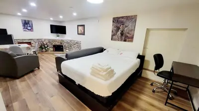 a bedroom with a bed and a living room with a fireplace at 4th Street Studio By Downtown and Airport in Calgary