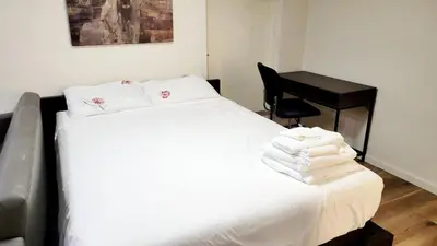 a bedroom with a bed with white sheets and a desk at 4th Street Studio By Downtown and Airport in Calgary