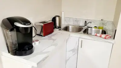 a kitchen counter with a coffee maker and a sink at 4th Street Studio By Downtown and Airport in Calgary