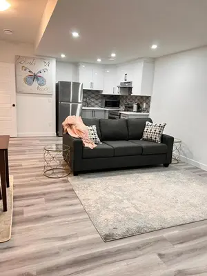 a living room with a black couch and a kitchen at Cozy Corner - 1 bedroom suite - 15 mins from airport in Calgary