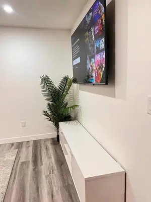 a living room with a white bench and a tv at Cozy Corner - 1 bedroom suite - 15 mins from airport in Calgary