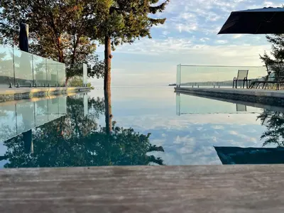 a reflection of a tree and a dock in the water at Cokely Cove Guesthouse - Oceanside Villa in Denman Island