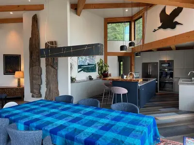 a kitchen and living room with a blue plaid table at Cokely Cove Guesthouse - Oceanside Villa in Denman Island