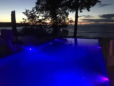 a swimming pool with blue lights in front of the water at Cokely Cove Guesthouse - Oceanside Villa in Denman Island