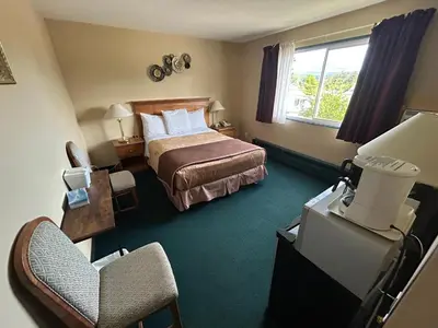 a hotel room with a bed and a chair at Marina Hotel in Port Alberni